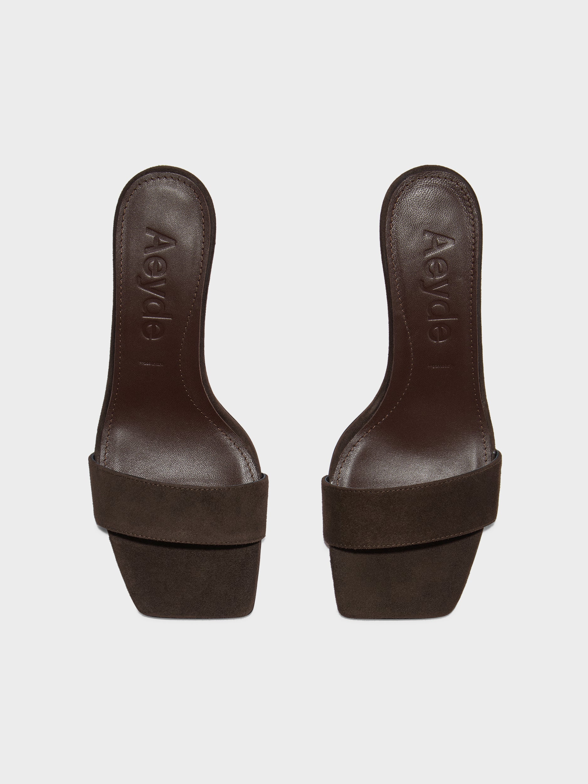 Brune ruskindssandaler med firkantet tå og "Aeyde" præget på indersålen.